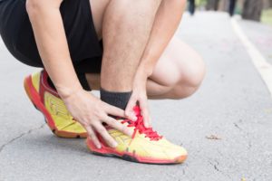 Man in sportswear holds ankle experiencing pain in his Achilles tendon from running